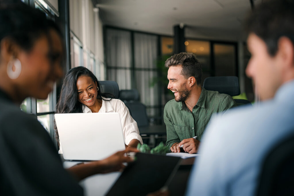 A group of employees sit around a desk, working together