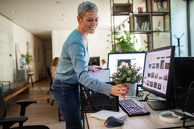 Woman placing small plant on her desk.